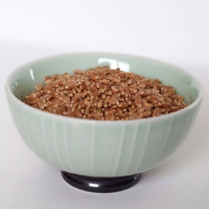 Buckwheat groats in a bowl on a white surface.