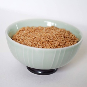 A bowl of brown rice sitting on a white surface.