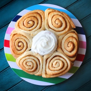 Cinnamon rolls on a plate with whipped cream.