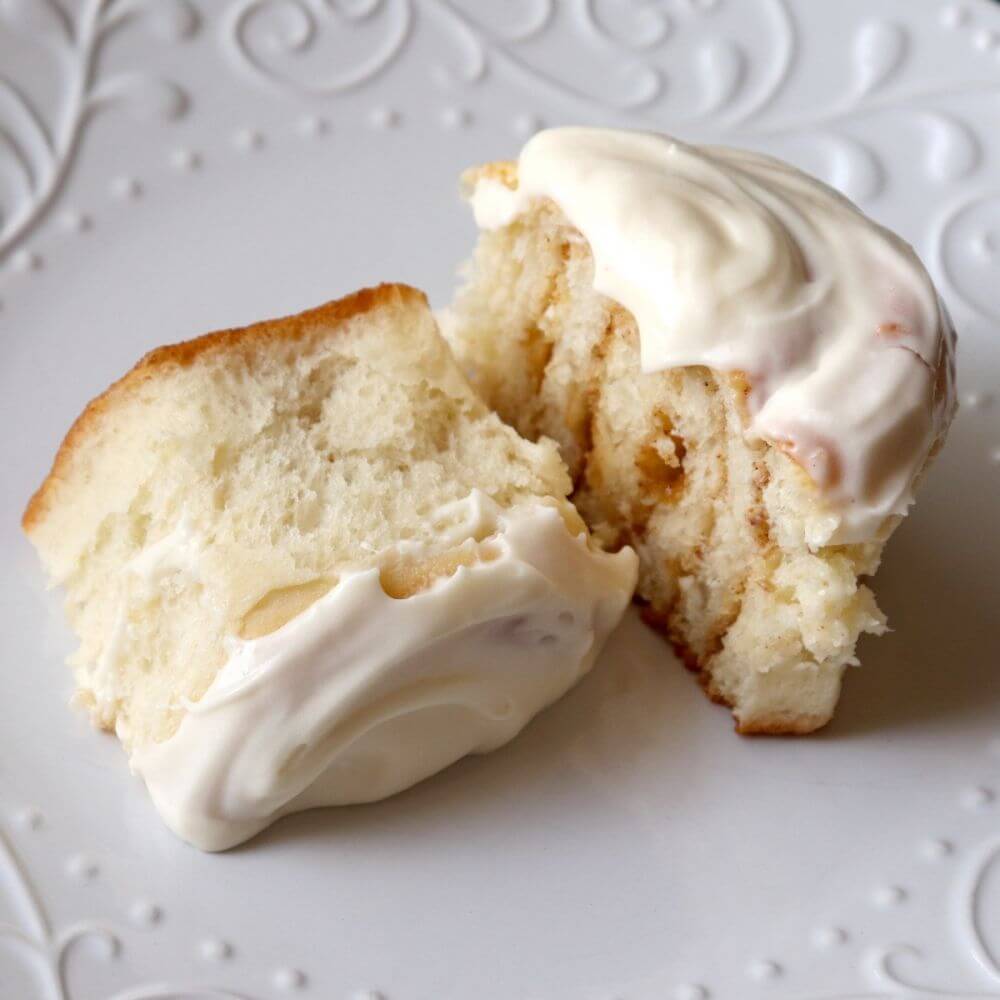 A piece of cinnamon roll with icing on a plate.
