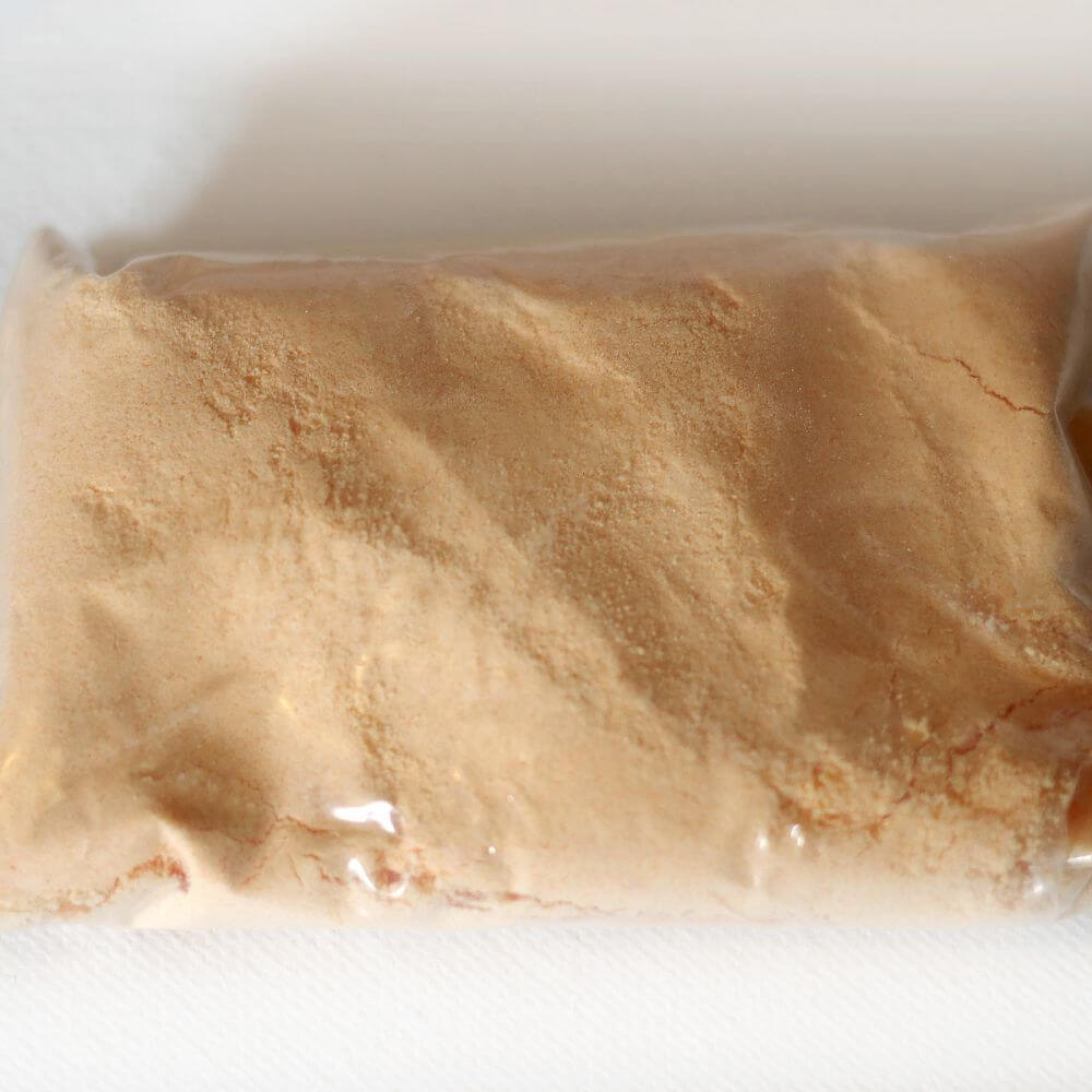A bag of brown powder sitting on top of a white surface.