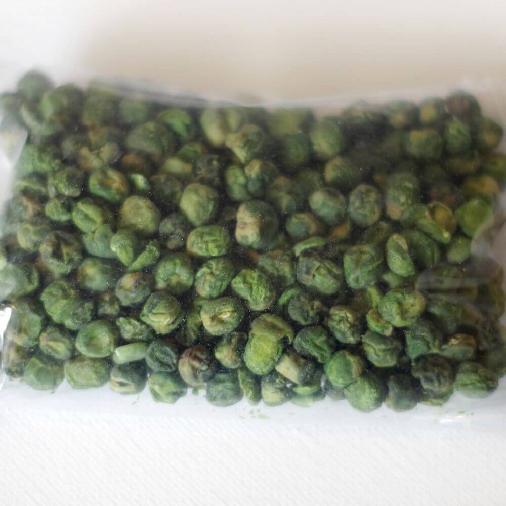 Green peas in a plastic bag on a white surface.