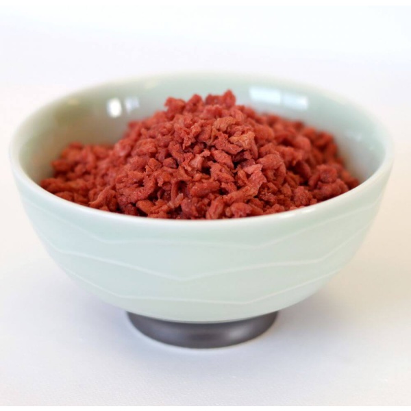 Red meat in a bowl on a white surface.