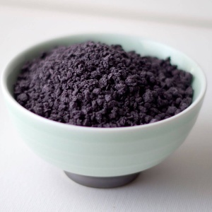 Purple powder in a bowl on a table.