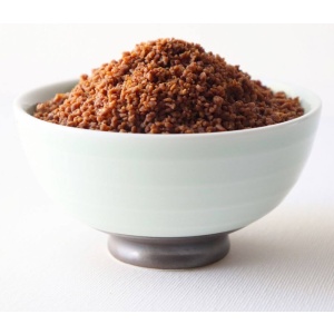 Brown sugar in a bowl on a white surface.