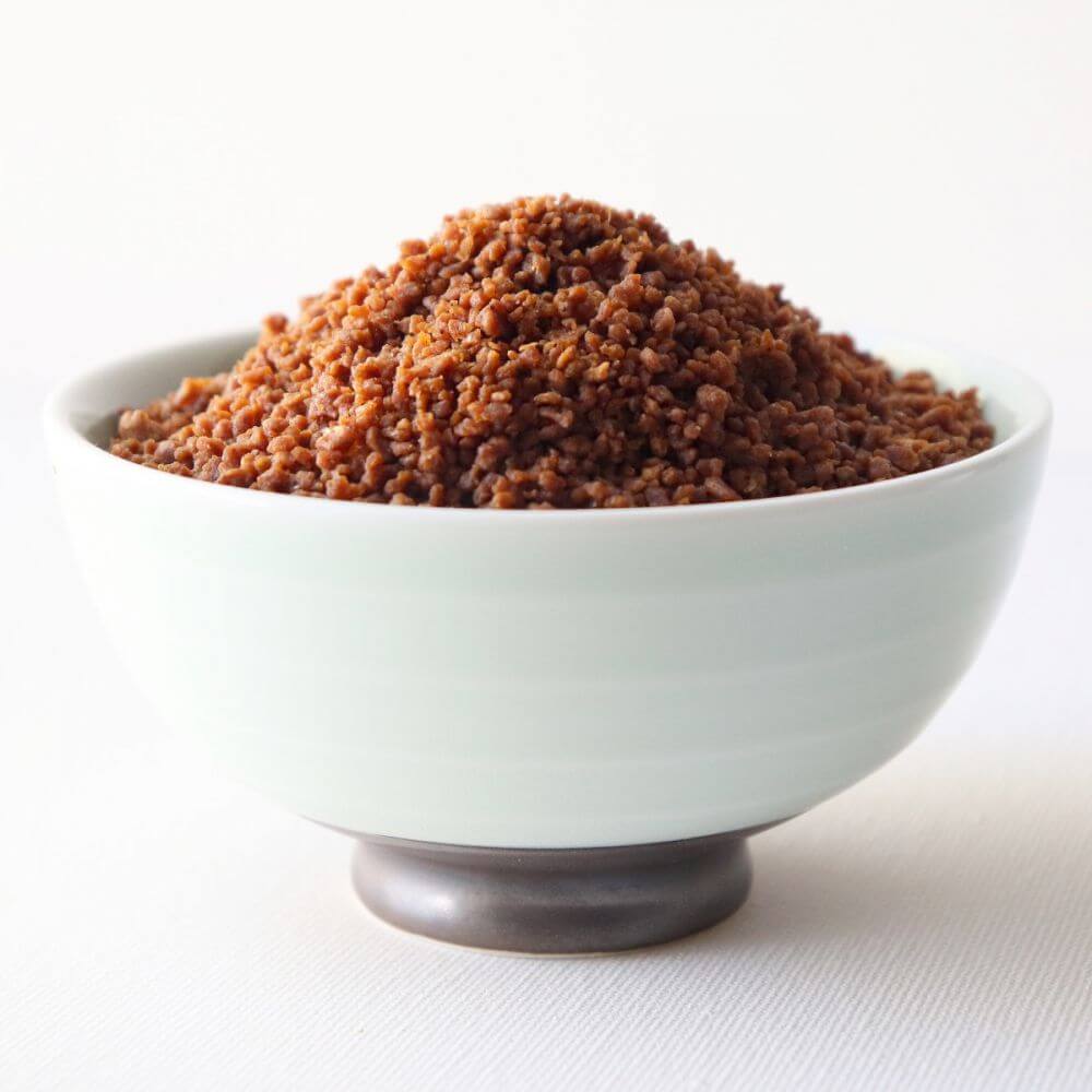 Brown sugar in a bowl on a white surface.