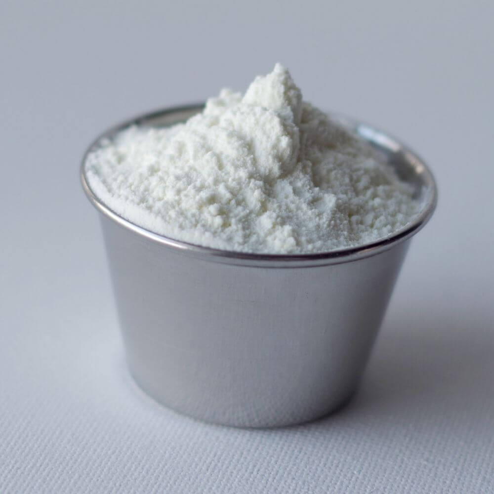 White powder in a small cup on a white surface.