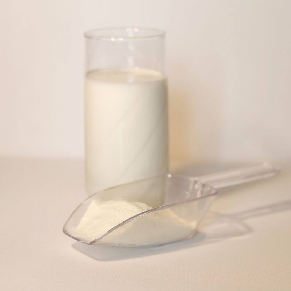 A glass of milk next to a scoop.