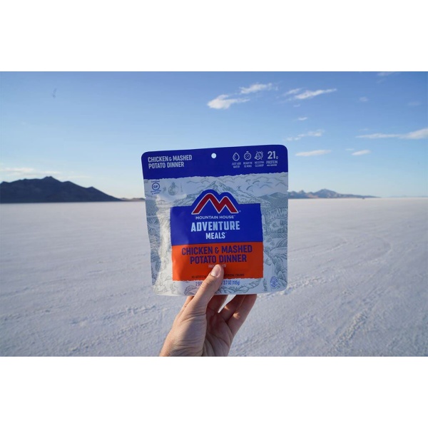 A person holding up a bag of Mountain House Chicken with Mashed Potatoes Mylar Pouch - Gluten-Free - 2 Servings - (SHIPS IN 1-2 WEEKS) salts.
