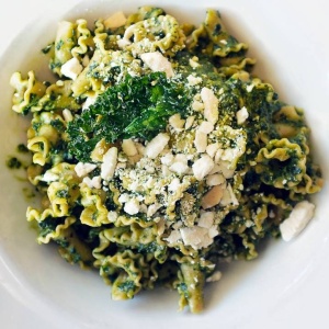A bowl of pasta with kale and almonds made with Rainy Day Foods Instant Basil Pesto Sauce.