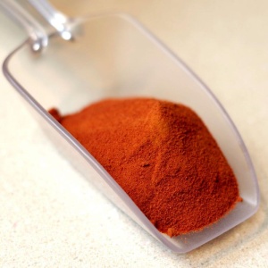 A scoop of red chili powder, perfect for emergency food storage, sits on a counter.