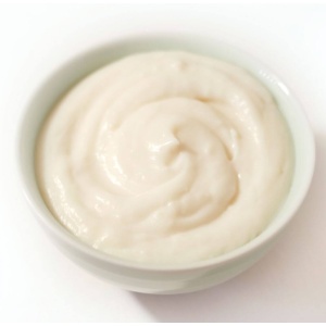 A bowl of white yogurt on a surface.