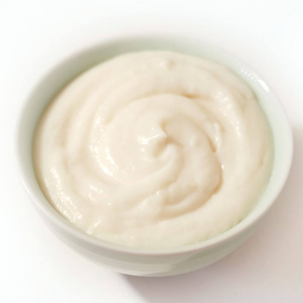 A bowl of white yogurt on a surface.