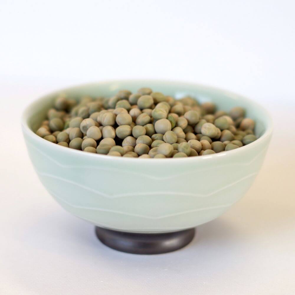 Emergency food storage: Peas in a bowl for long-term preparedness on a white surface.