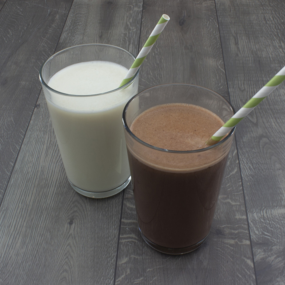 A glass of milk and a Augason Farms Minuteman 24-Hour Meal Kit - 6 Pack - (SHIPS IN 1-2 WEEKS) of chocolate milk.