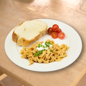 A plate of pasta and bread on a wooden table, featuring Heaven's Harvest Non-GMO Freeze-Dried 1-Month Lunch and Dinner Entree Pail Kit.