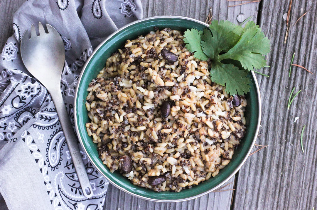 A bowl of brown rice with nuts and a spoon on a wooden table, available in an 18-pack case.