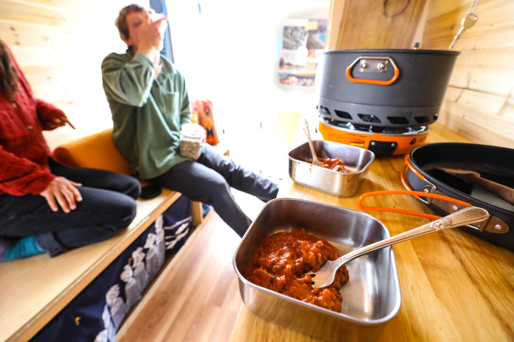 Two people enjoying Campfare Chicken Tikka Masala in a tiny house.
