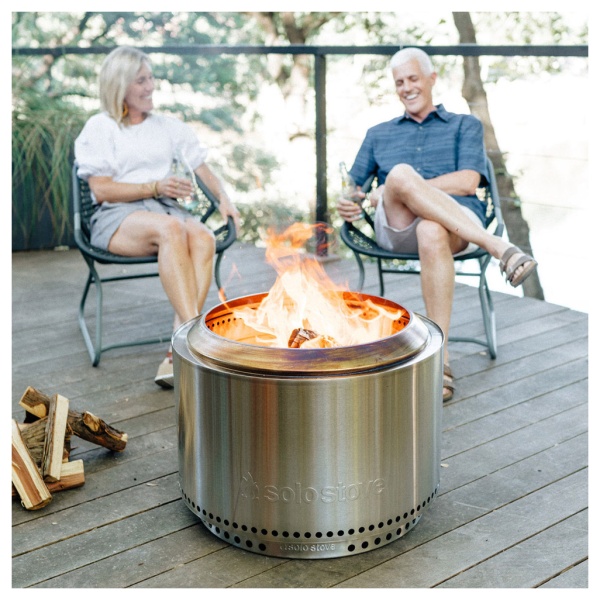 Two people enjoying a fire pit on a deck.