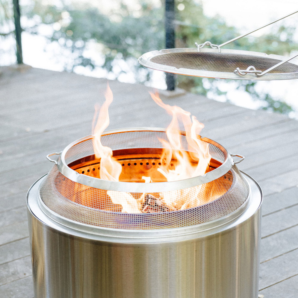 A portable stainless steel fire pit on a wooden deck.