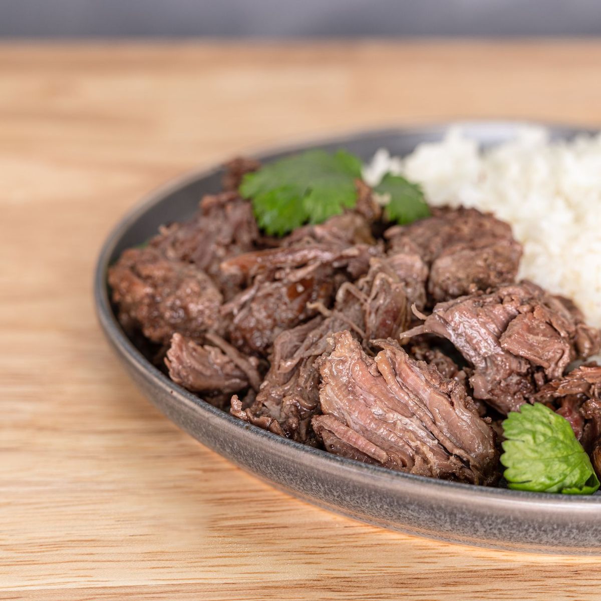 A plate of beef and rice, used for emergency food storage, on a wooden table.