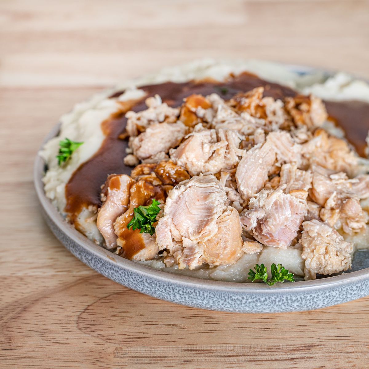 A plate of chicken and gravy on a wooden table, perfect for emergency food storage.
