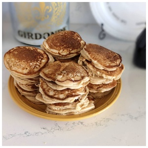 A Wise Company stack of pancakes on a plate next to a bottle of whiskey.