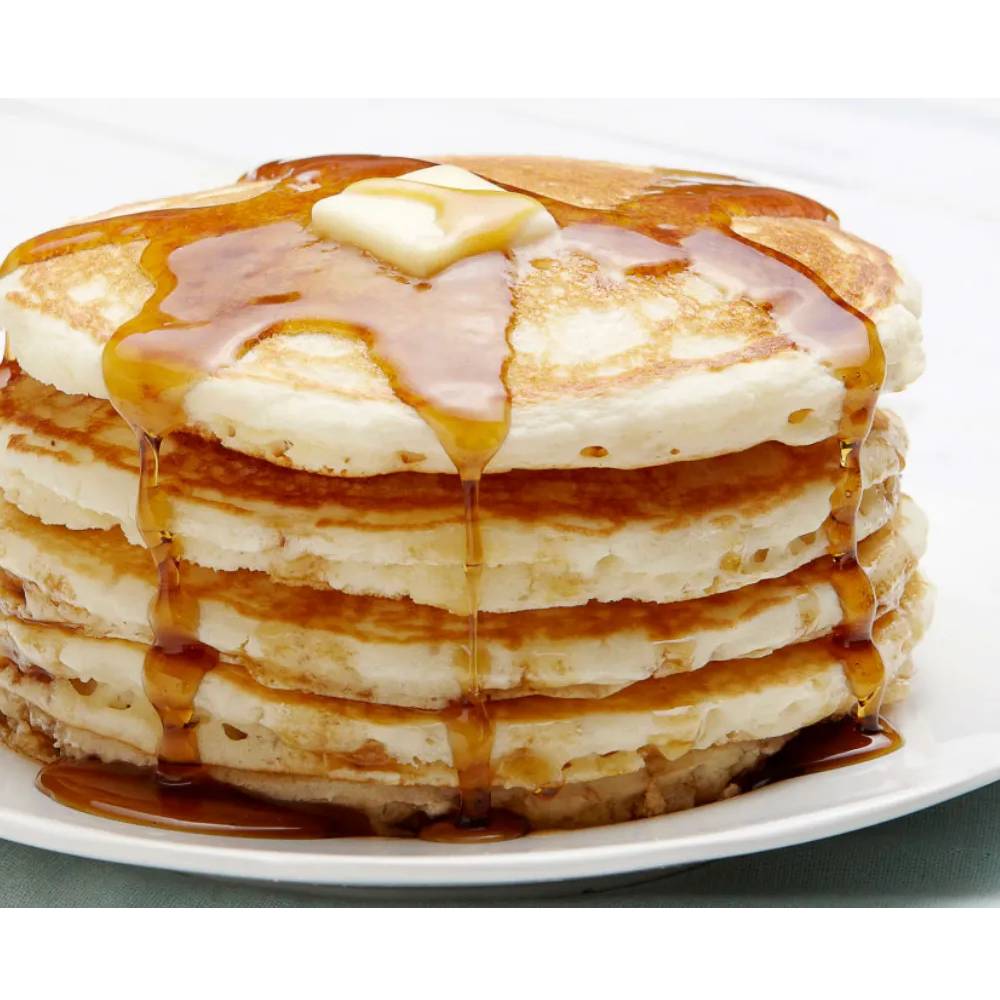 A stack of buttermilk pancakes with syrup and butter on a plate.