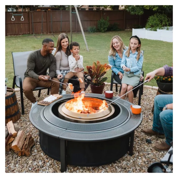 A group of people enjoying a portable Solo Stove fire pit in a backyard.