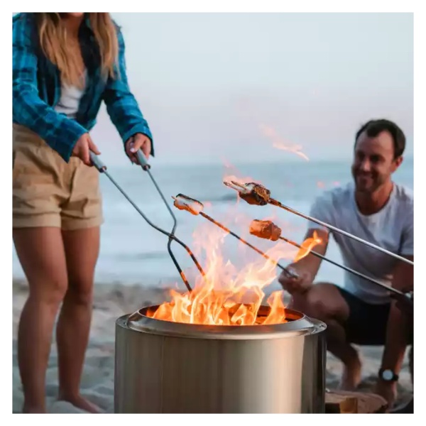 A couple grilling on the beach with a portable and "smokeless" Solo Stove Stainless Steel Bonfire.