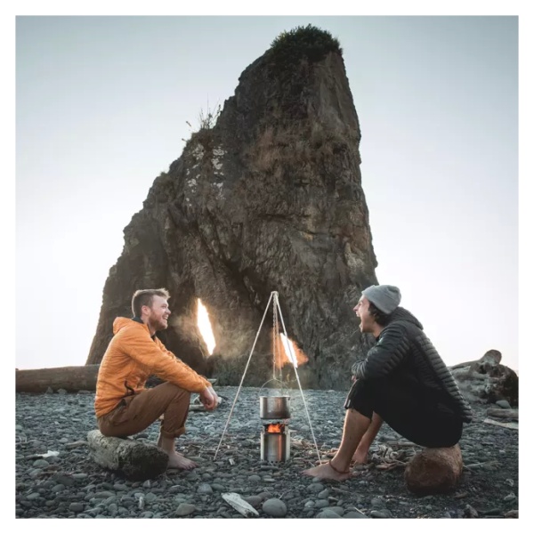 Two men sitting around a portable campfire on the beach, using a solo stove stainless steel campfire gear kit.