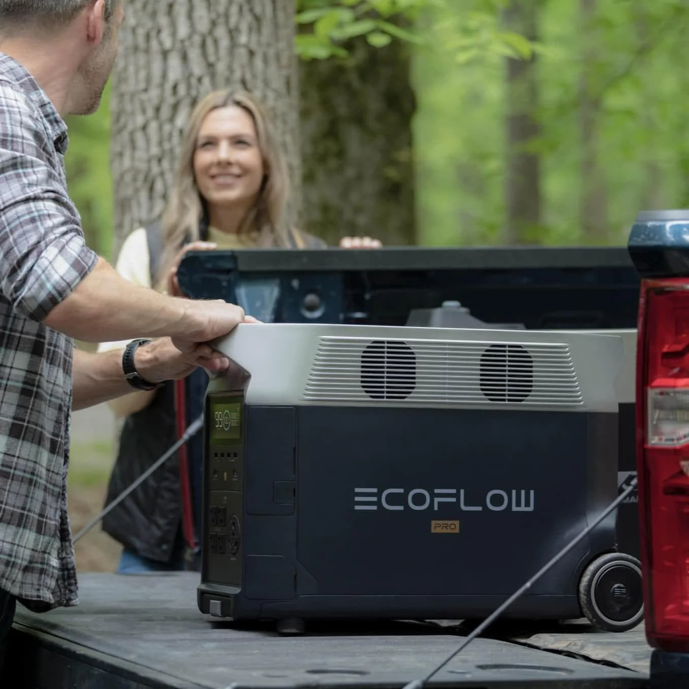 A man and woman are installing an EcoFlow DELTA Pro Portable Power Station in the back of a pickup truck.