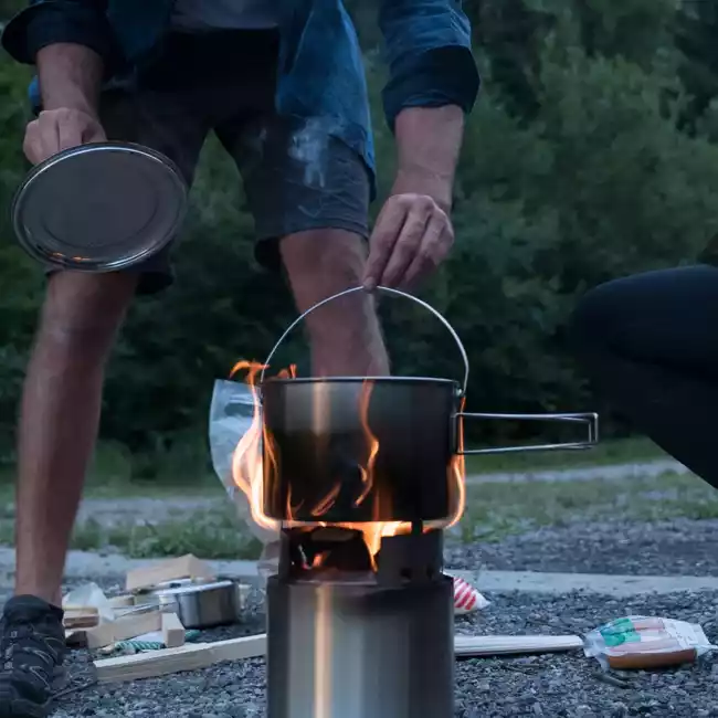 A man and woman cooking on a portable camp stove.