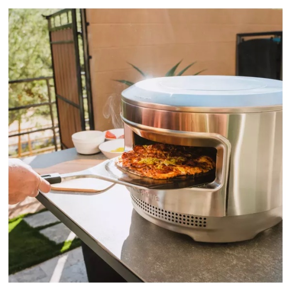 A person is placing food into a portable pizza oven.