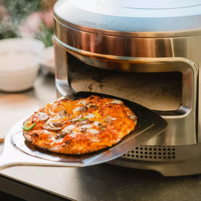 A portable and "smokeless" pizza oven cooks a pizza.