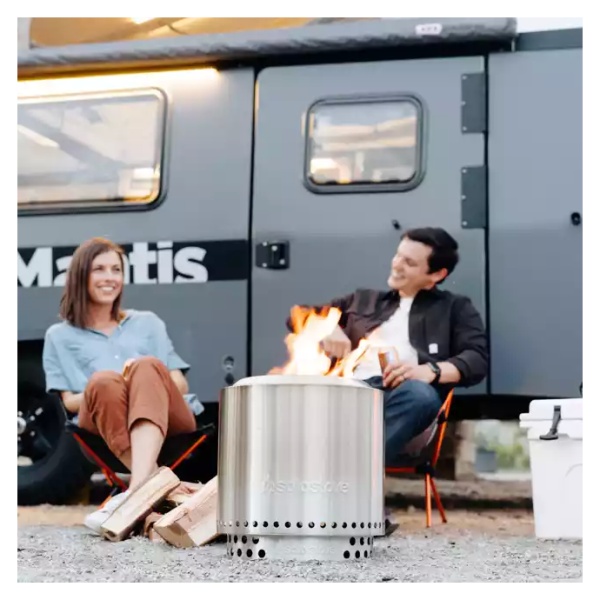 A couple enjoys a portable and smokeless fire pit in front of their camper with the Solo Stove Stainless Steel Ranger Essential Bundle 2.0.