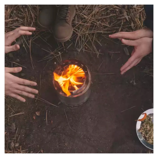 A group of people sitting around a portable campfire.
