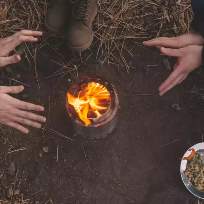 A group of people sitting around a portable campfire.