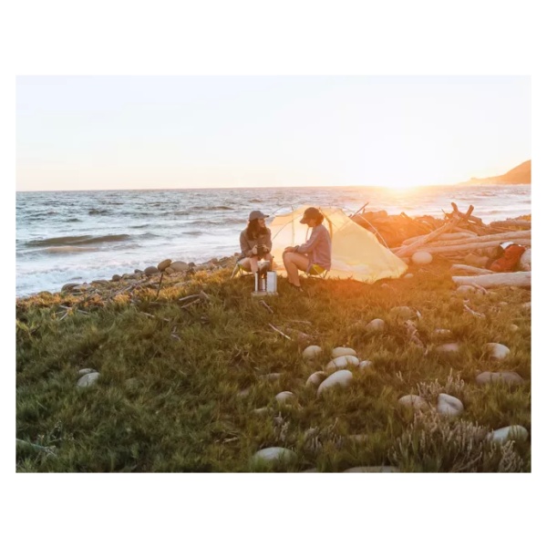 Two people enjoying a beach sunset in a portable tent.