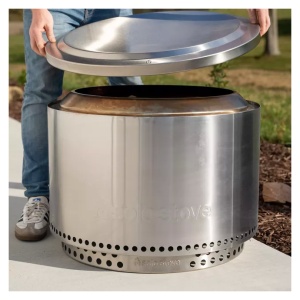 A man opening up a portable stainless steel fire pit.