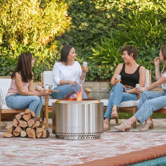 A group of women sitting around a "smokeless" fire pit.