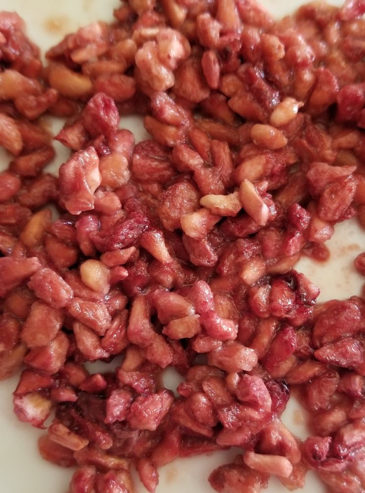 A pile of dried cranberries on a white plate with Rainy Day Foods Freeze-Dried Pomegranate Arils #10 Cans.