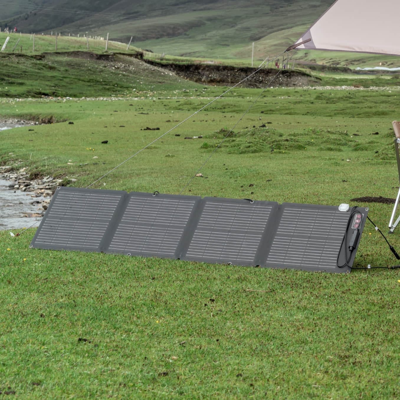 The EcoFlow 110W Portable Solar Panel is set up in the grass next to a tent.