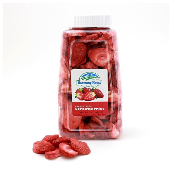 A jar of sliced Harmony House Freeze Dried Strawberries sitting on a white surface.