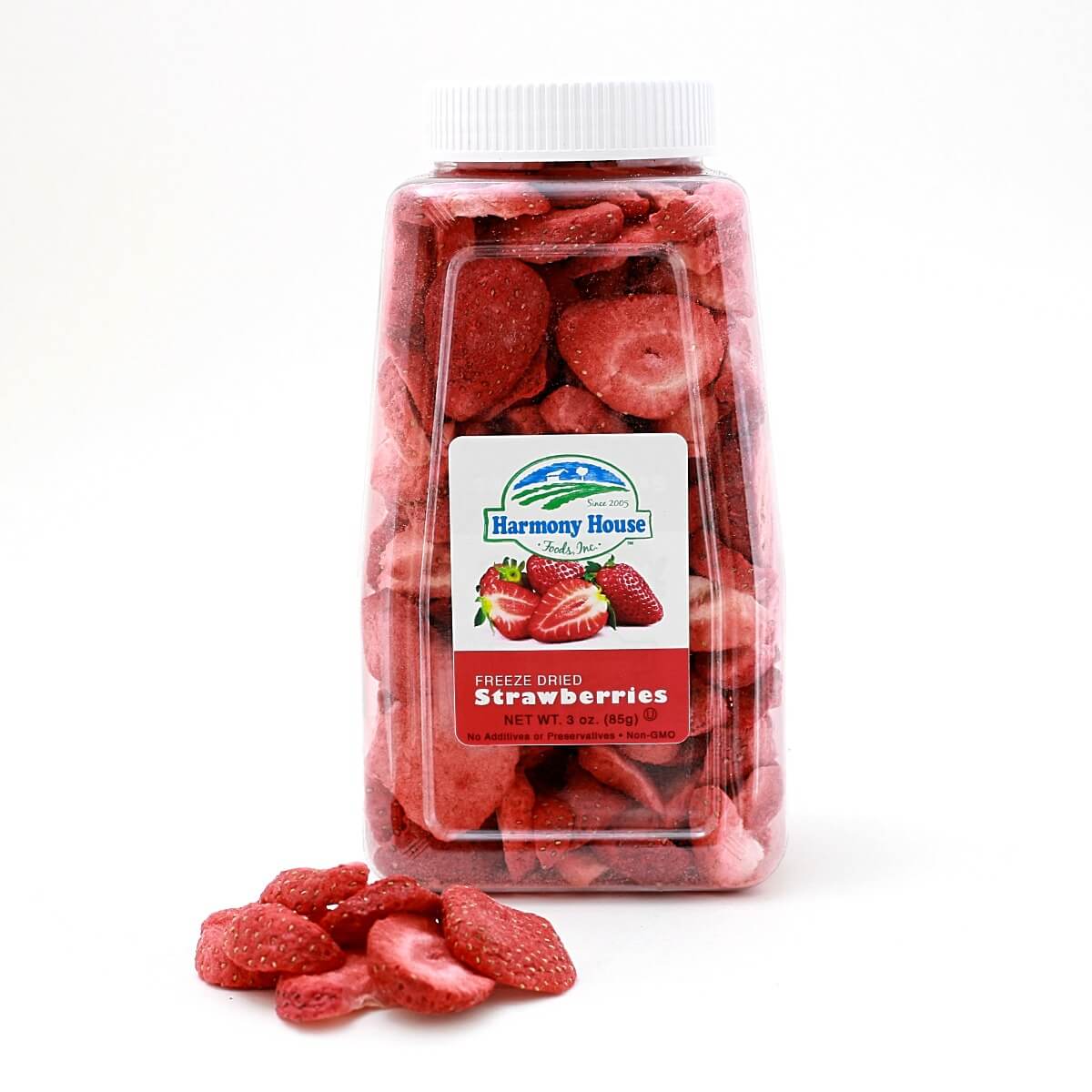 A jar of sliced Harmony House Freeze Dried Strawberries sitting on a white surface.