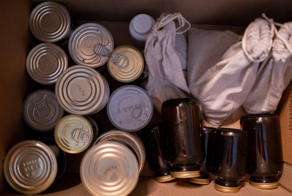 A box filled with various cans and bottles, emphasizing the history of emergency food storage.