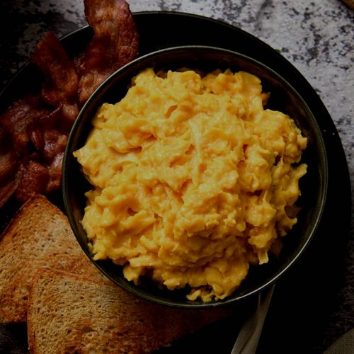A bowl of scrambled eggs with bacon and toast, now with reconstituted powdered eggs.