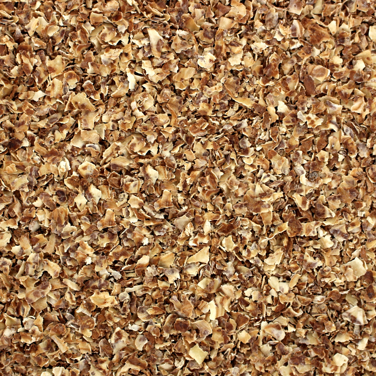 A close up of a pile of brown chips, featuring Harmony House Pinto Bean Flakes.