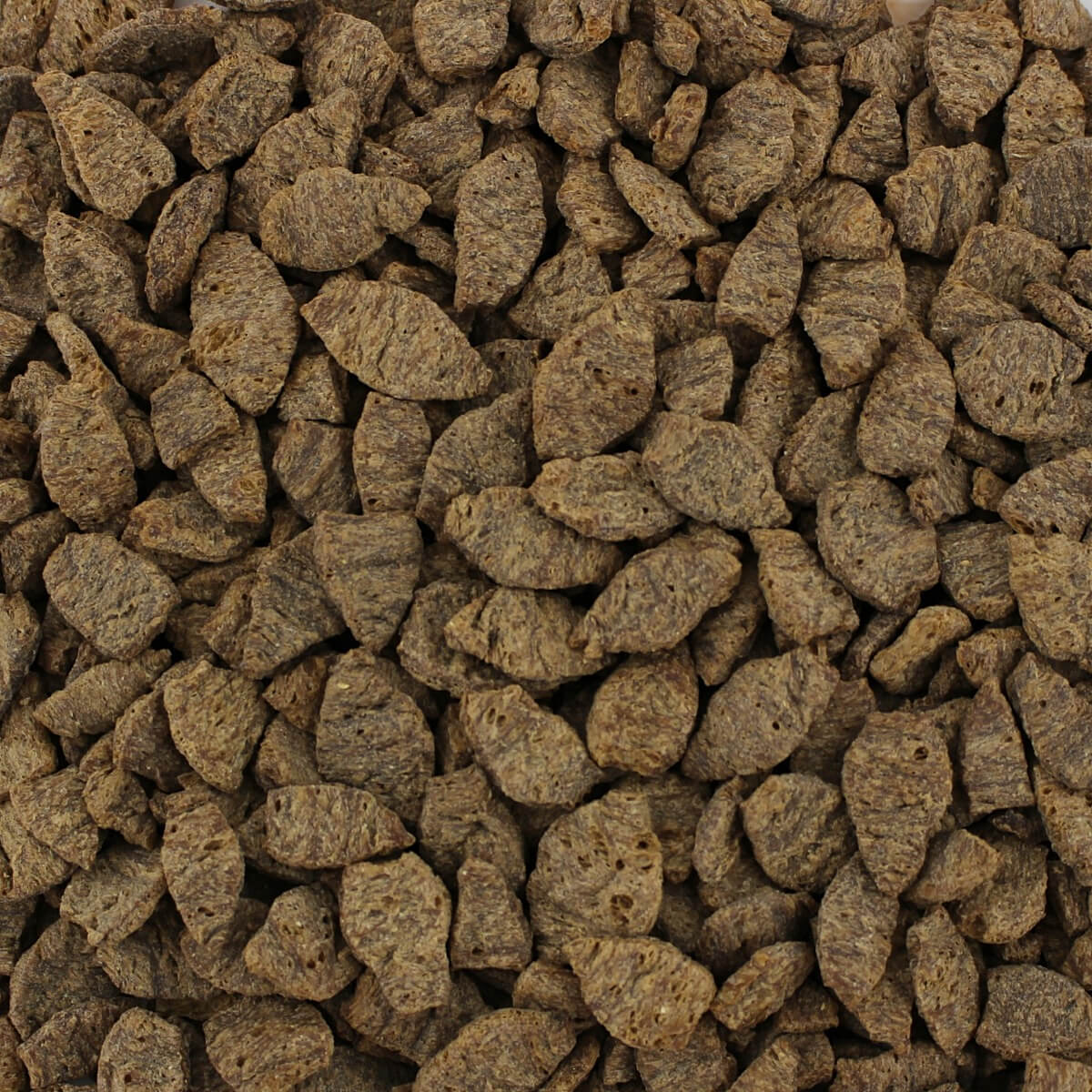 A pile of brown dog food on a white Harmony House Deluxe Plant-Based Protein Sampler (12 Zip Pouches) background.