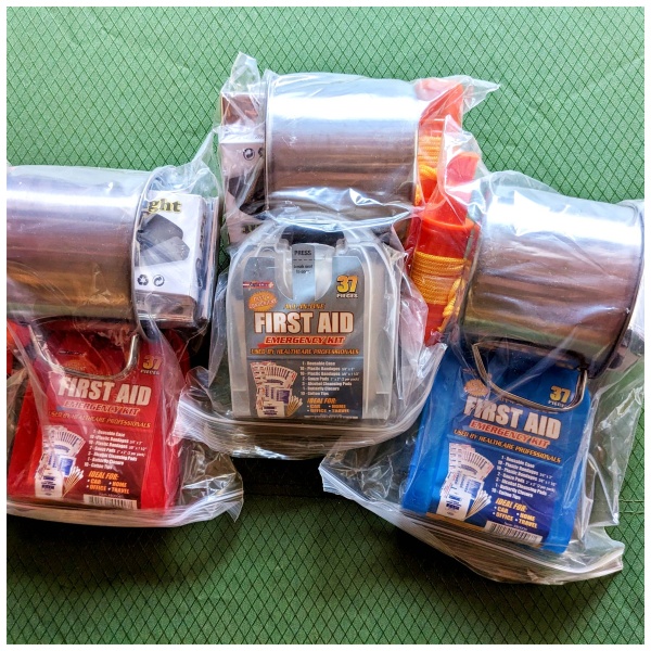 Three emergency first aid kits in plastic bags are available on a table.